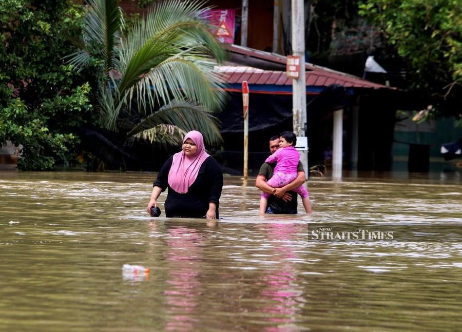 Residents of Kampung Siram, Rantau Panjang, wade through the floodwaters. -NSTP/NIK ABDULLAH NIK OMAR