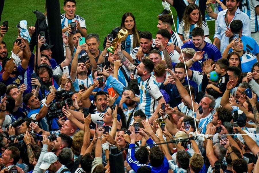 Argentina's Lionel Messi holds the winners trophy as he celebrates with fans after Argentina won the World Cup final match against France at the Lusail Stadium in Lusail, Qatar. - AP PIC