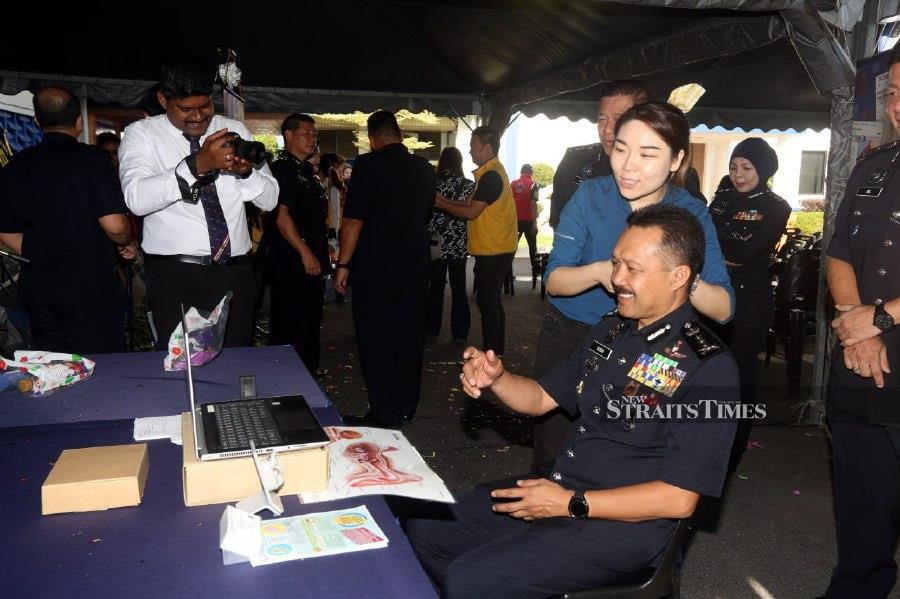 Perak police chief Datuk Seri Mohd Yusri Hassan Basri getting his ear checked during the Healthy Eating Active Living programme in Ipoh. -NSTP/L. MANIMARAN