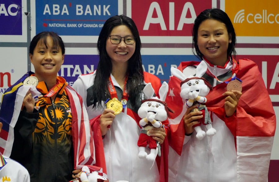 Singapore's Letitia En Yi Sim celebrates after winning gold medal alongside silver medalist Malaysia's Phee Jinq En and bronze medalist Singapore's Christie Chue in the women's 100m Breaststroke final. -- REUTERS
