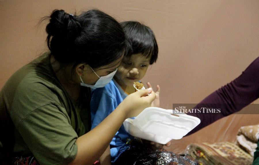 A mother feeds her child as the seek shelter at the at the Sembulan temporary relief centre. -NSTP/MALAI ROSMAH TUAH. 