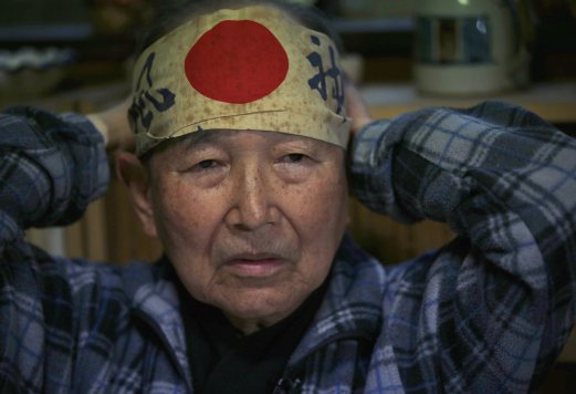 Japanese Katsumoto Saotome, 82, a survivor of Great Tokyo Air Raids in 1945, wears a headband with words reading 'Kamikaze' on it, which he carried during an evacuation in the bombing during an interview with Reuters at his home in Tokyo March 4, 2015. Now, as memories fade of how civilians suffered during World War Two - suffering Saotome blames on Japan's wartime leaders who thought of their citizens as "weeds" - the author fears Japan may be marching towards war again. Picture taken March 4. REUTERS 