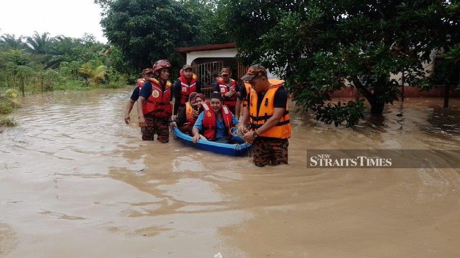  Firemen evacuate residents of Kampung Sentosa Damai, Pasir Gudang, following the floods. - Pix courtesy of Civil Defence Force