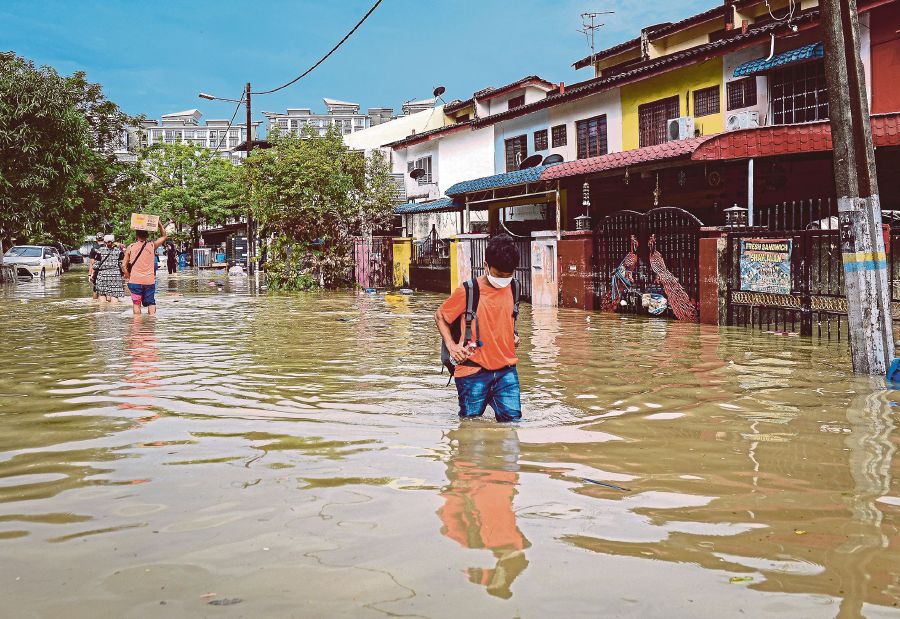 This file pic dated December 22, 2021, shows residents in Taman Sri Muda wading through floodwaters following heavy rain few days before. - BERNAMA PIC