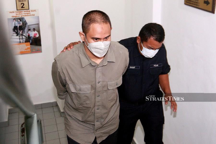Mohamad Safiq Rosli (left) is escorted by a policeman at the Shah Alam magistrate’s court ahead of the trial. -NSTP/FAIZ ANUAR