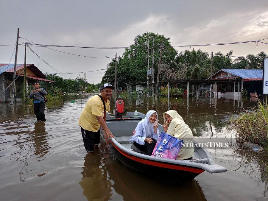 Mohd Hamka uses a boat to transport students including his daughter Puteri Nur Hanisah (centre) to a school in Teluk Intan, following the floods. - NSTP/MUHAMAD LOKMAN KHAIRI.