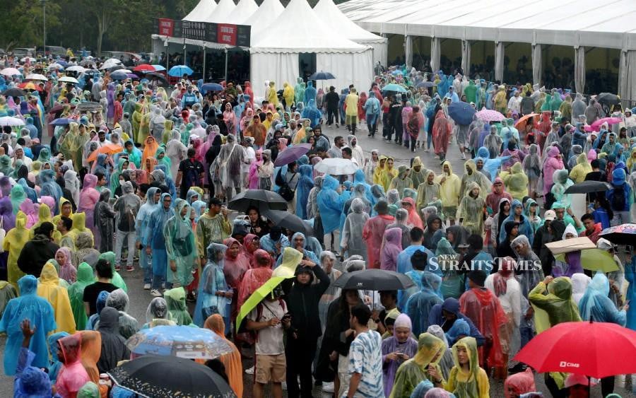 Fans wearing colourful plastic raincoats during the rain, while waiting to enter the Bukit Jalil National Stadium ahead of the Coldplay concert in Kuala Lumpur. - NSTP/HAIRUL ANUAR RAHIM