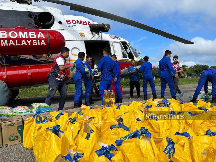 Firemen and Civil Defence Force personnel help carry the food items to be transported to Gob, Pos Bihai, Pos Balar, Pos Belatim and Pos Simpor. - NSTP/Paya Linda Yahya 