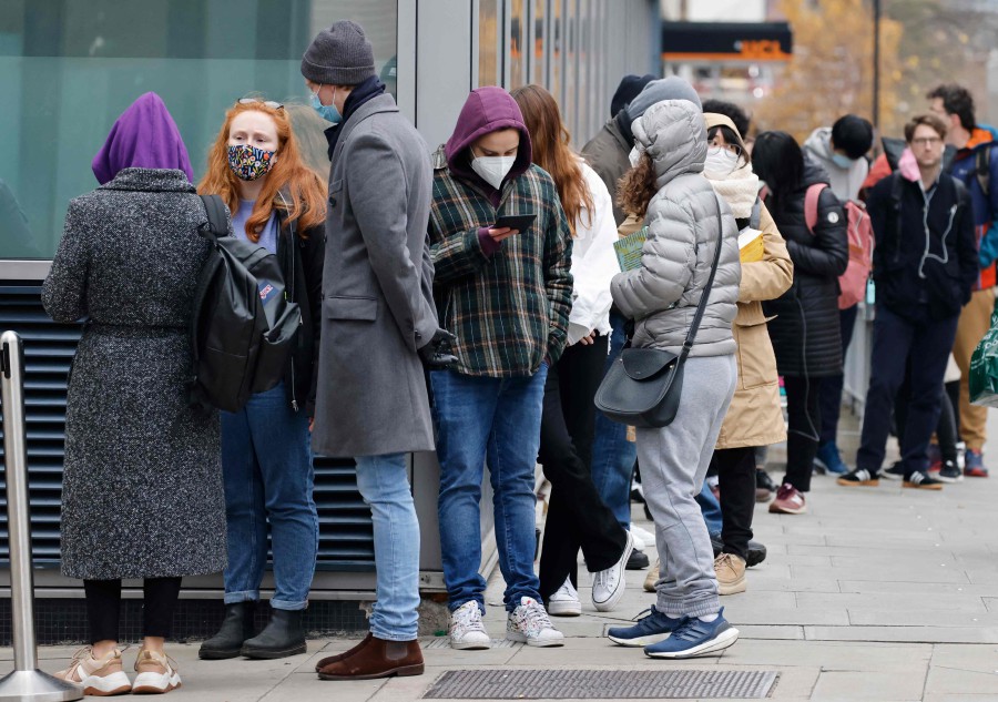 People wait in a queue outside University College London Hospital vaccination centre to receive their the Covid-19 vaccine or booster in London. - AFP PIC