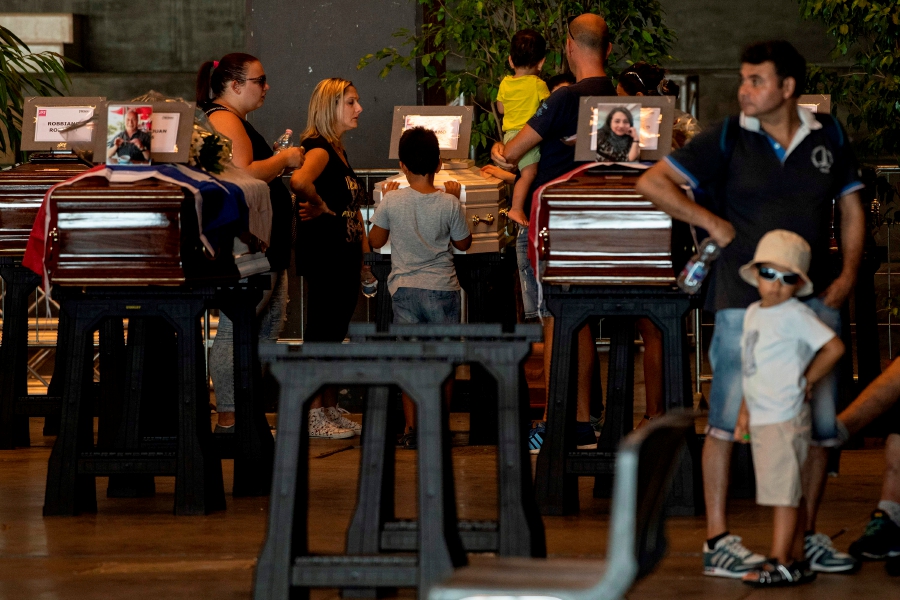 Relatives pray and pay their respects next to a coffin of a victim of the Morandi bridge's collapse in Genoa, at a funerary home installed at the fairground, in Genoa, on August 17, 2018. - Italy prepares to pay homage to the victims of the deadly bridge collapse as rescuers use diggers to claw through mountains of rubble in a desperate search for survivors, but some families are reportedly refusing the join the state memorial ceremony. A vast span of the Morandi bridge caved in during a heavy rainstorm in the northern port city of Genoa on August 14, 2018, sending about 35 cars and several trucks plunging 45 metres (150 feet) onto railway tracks below and killing at least 39 people. — AFP pic 