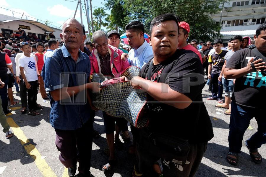 Members of the public help carry a fan who had fainted at the Sultan Ismail Nasiruddin Shah Stadium. - NSTP/GHAZALI KORI