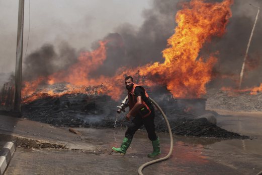 A Palestinian fire-fighter tries to extinguish a fire which police said was caused by an Israeli tank shelling in the industrial area in the east of Gaza City July 12, 2014. Israel pounded Palestinian militants in the Gaza Strip on Saturday for a fifth day, killing nine people including two disabled women according to medics, and showed no sign of pausing despite international pressure to negotiate a ceasefire. REUTERS