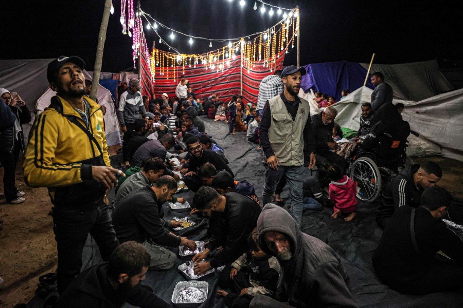 Palestinians share an iftar meal, the breaking of fast, on the first day of the Muslim holy fasting month of Ramadan, at a camp for displaced people in Rafah in the southern Gaza Strip. - AFP PIC