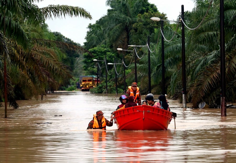 Firemen evacuate Kampung Batu 20 and Kampung Bukit Dagang residents in Sungai Tiram following the floods. - BERNAMA PIC
