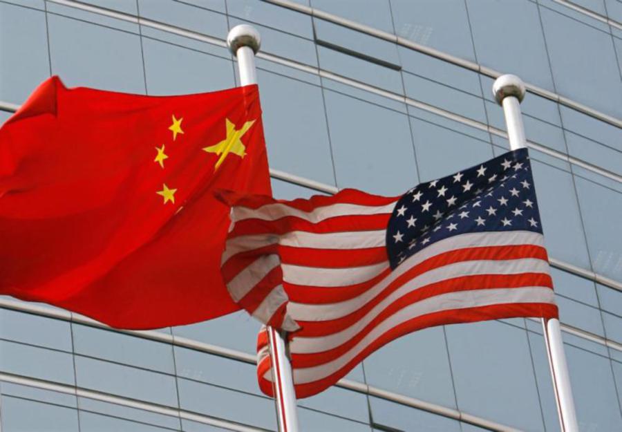 A US and a Chinese flag wave outside a commercial building in Beijing. (TEH ENG KOON/AFP/Getty Images)