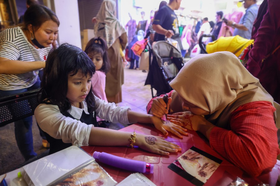  A henna artists attending to her customer at the Jalan Tuanku Abdul Rahman bazaar in Kuala Lumpur. - BERNAMA PIC