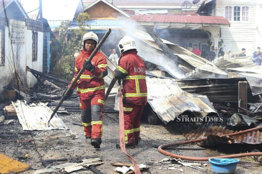 Firemen on the scene after seven houses were destroyed in a fire at Kampung Sireh, in Kota Baru. -NSTP/NIK ABDULLAH NIK OMAR