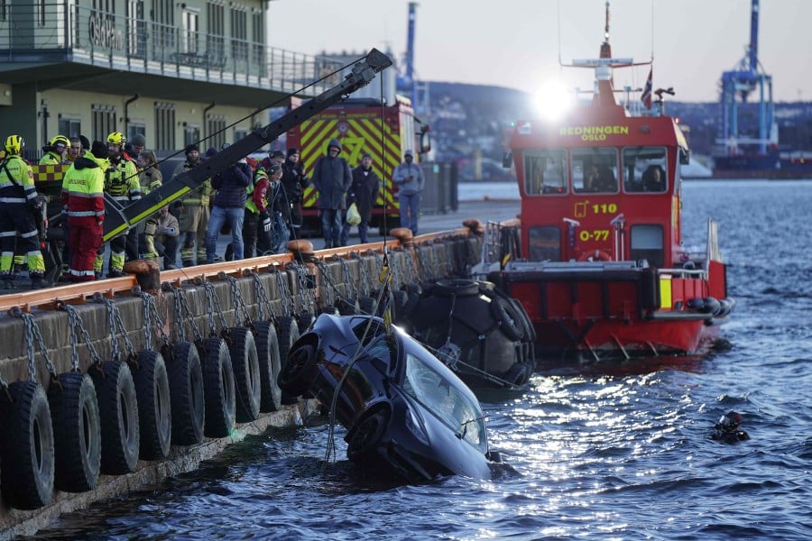 Rescue personnel retrieve a Tesla car from the water after driving out into the Oslofjord on February 1, 2024 in Oslo. - AFP PIC