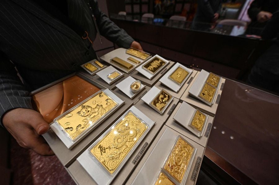 A shop assistant displaying gold products at a Chow Tai Fook jewellery store in Beijing. Elaborate traditional pieces created by master goldsmiths have always been popular in China — Younger people, who are increasingly keen to buy gold, seeing it as a safe investment in uncertain economic times. - AFP pic