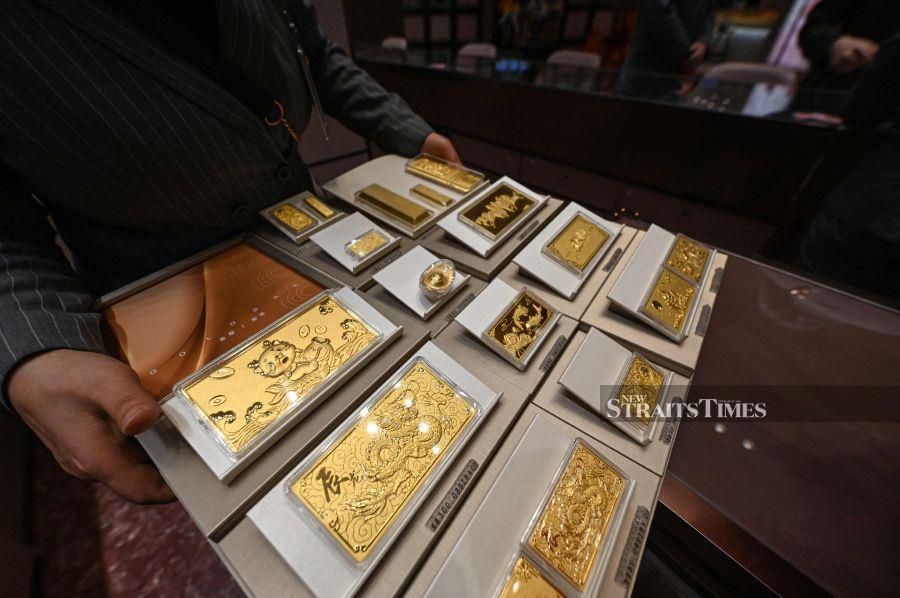 This photo taken on February 5, 2024 shows a shop assistant displaying gold products . (Photo by Jade GAO / AFP) 