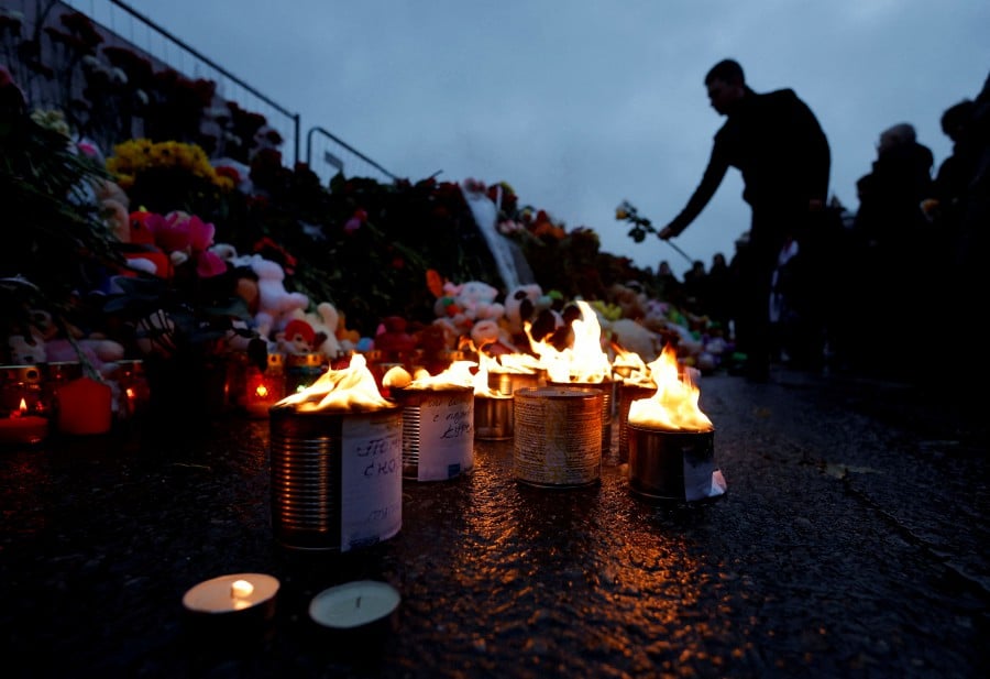 A man lays flowers at a makeshift memorial to the victims of a shooting attack, set up outside the Crocus City Hall concert venue in the Moscow Region, Russia. - REUTERS PIC