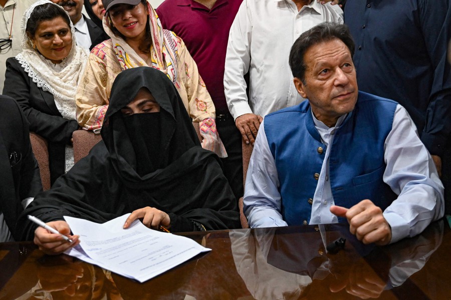 Pakistan's former Prime Minister, Imran Khan (R) along with his wife Bushra Bibi (L) looks on as he signs surety bonds for bail in various cases, at a registrar office in the High court, in Lahore on July 17, 2023. - AFP PIC