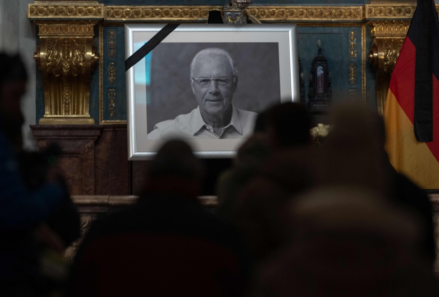 Members of the public line up to sign the book of condolences for German football legend Franz Beckenbauer with his picture on display at the Hofkapelle in Munich. - AFP PIC