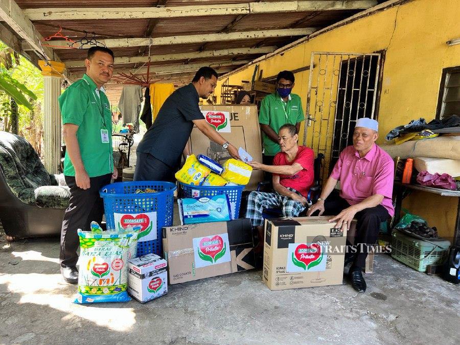  (from left) Kedah Youth and Sports Committee chairman Muhammad Radhi Mat Din, Econsave Cash and Carry Sdn Bhd northern region general manager Zamzuri Mansor and Bukit Pinang assemblyman Datuk Wan Romani Wan Salim (far right) presenting a wheelchair and household necessities to Kedah football legend Abdul Rahman Tasu (sitting, right) at his home in Langgar. - NSTP/ADIE ZULKIFLI