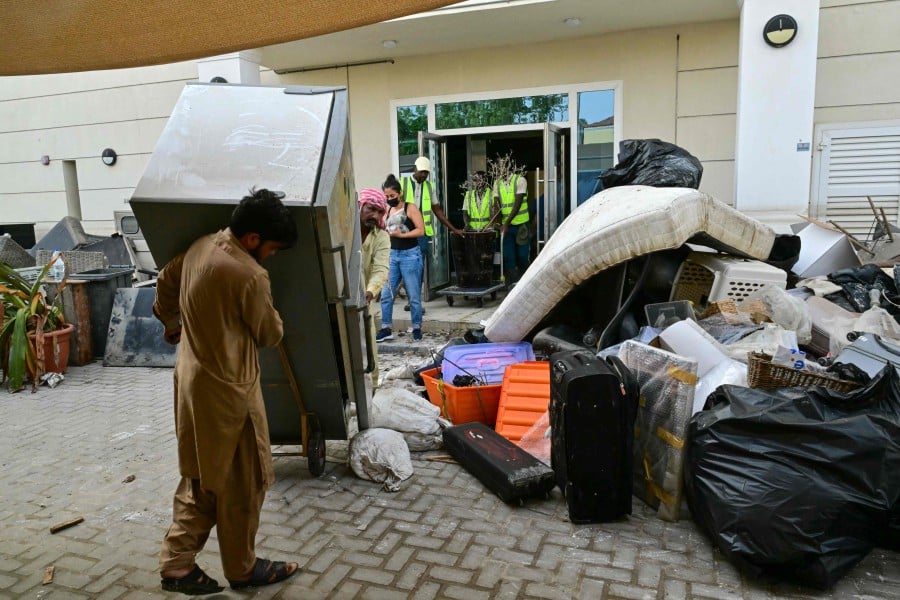 Workers clean a building in Dubai's Green Community neighbourhood on May 1, which was damaged by floods a week earlier. -AFP PIC