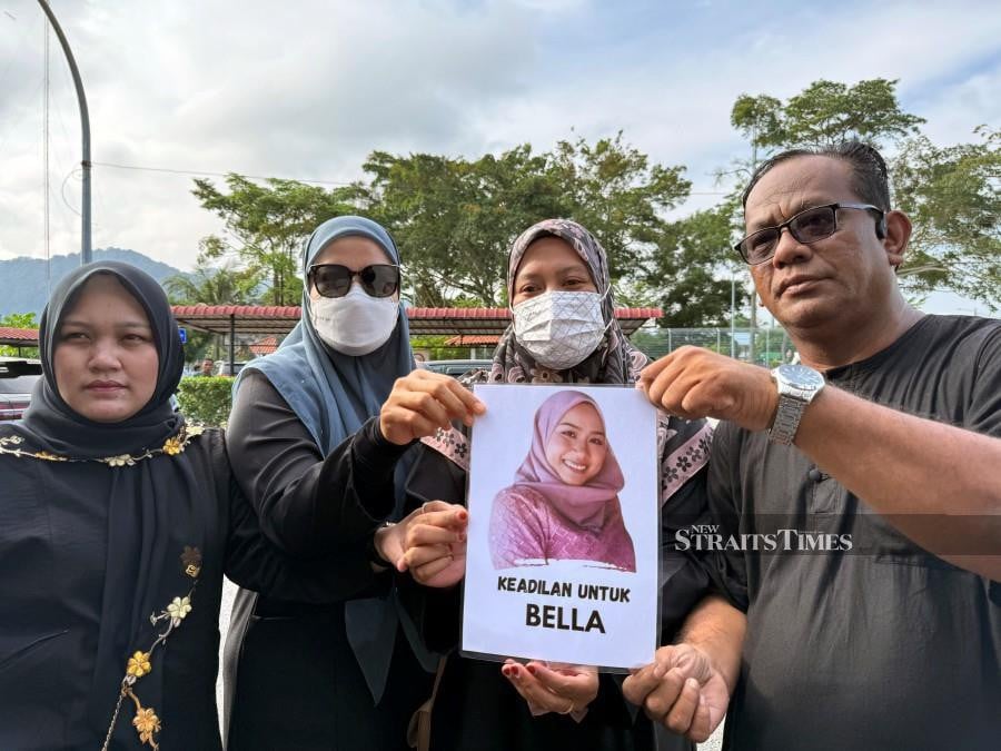 Family members of the deceased hold a placard at the Batu Pahat magistrate’s court ahead of the trial. - NSTP/NUR AISYAH MAZALAN