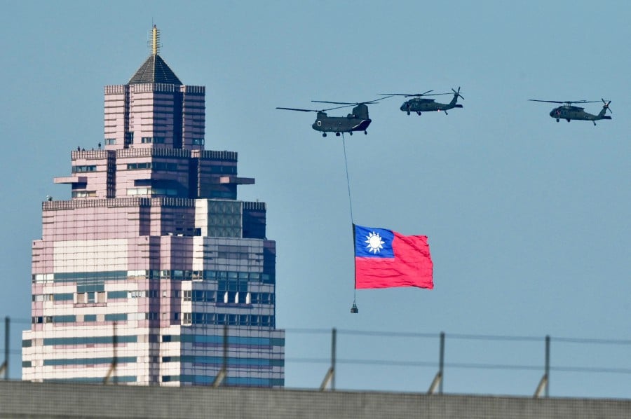 A US-made CH-47SD helicopter flies a national flag past a building during a rehearsal ahead of the May 20 Taiwan President-elect Lai Ching-te’s inauguration ceremony in Taipei. - AFP PIC