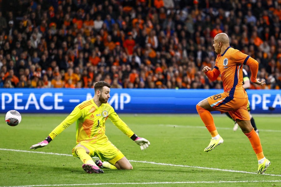 Netherlands' forward Donyell Malen (R) shoots to score the fourth goal during the match against Scotland at the Johan Cruijff Arena in Amsterdam. - AFP PIC