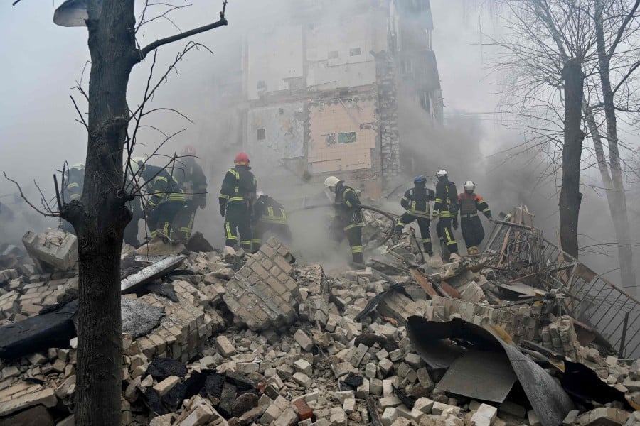 Ukrainian rescue workers and firefighters clear debris at the site of a missile attack in Kharkiv. - AFP PIC