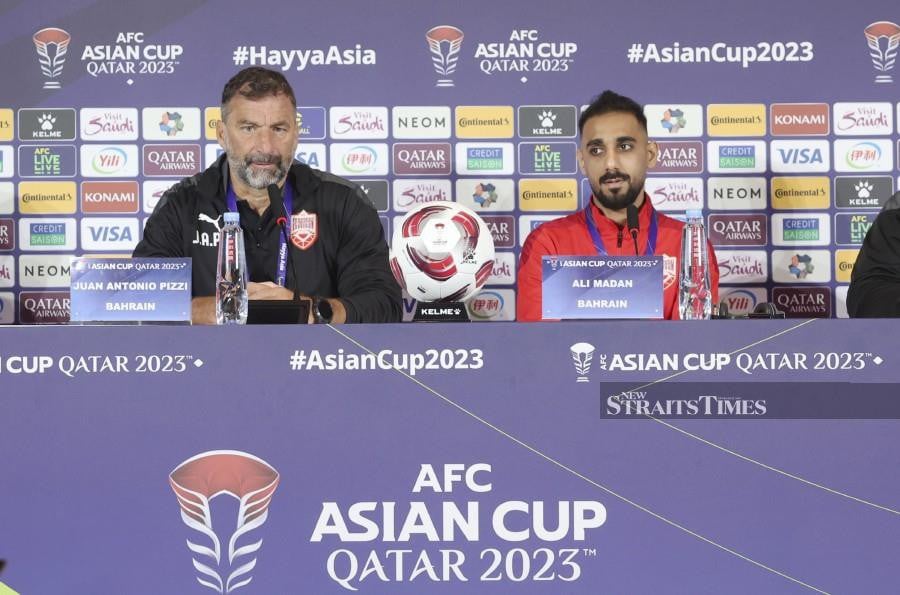 Bahrain’s coach Juan Antonio Pizzi (left) with his captain Ali Madan speaking to reporters during a press conference in Doha. -NSTP/HAIRUL ANUAR RAHIM.