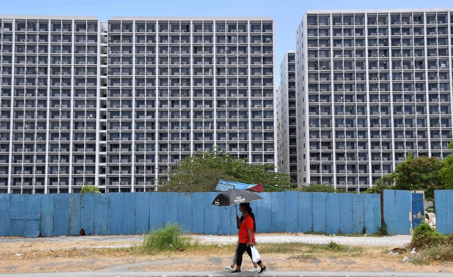 This picture shows woman walking past buildings with air conditioning units in Manila. - AFP PIC