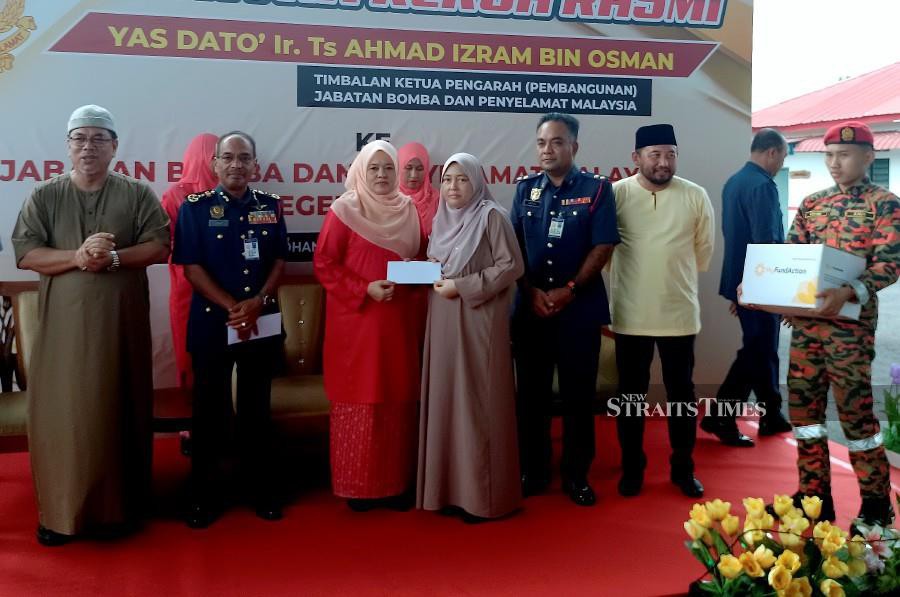 Wives of Fire Personnel and Women Fire Personnel (Perisma) chairman Datin Batiyah Bakar (3rd-left) presenting the aid to firemen’s widow, during the visit of Malaysian Fire and Rescue Department deputy director-general (Development) Datuk Ahmad Izram Osman (2nd-left) in Kampung Solok Duku. - BERNAMA PIC 