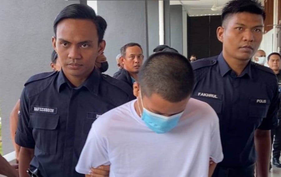 Policemen escort Mohammad Haikal ahead of his trial at the Batu Pahat magistrate’s court. -NSTP/Alias Abd Rani