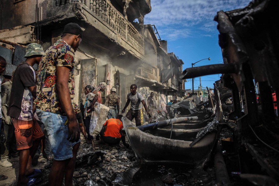 Men pick up aluminium pieces at the site where a tanker truck exploded in Cap-Haitien, Haiti. - AFP PIC