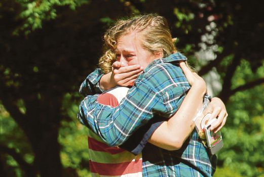 Two women embrace near a prayer circle on the campus of Seattle Pacific University, Friday, June 6, 2014 in Seattle. Classes were cancelled Friday following a shooting at Otto Miller Hall Thursday afternoon. A 19-year-old man was fatally shot and two other young people were wounded after a gunman entered the foyer and started shooting. Aaron R. Ybarra, 26, was booked into the King County Jail late Thursday for investigation of homicide, according to police and the jail roster. AP Photo