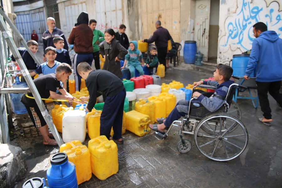 Palestinian children collect water at Zaytoun neighbourhood in Gaza City on March 31, 2024. - AFP PIC