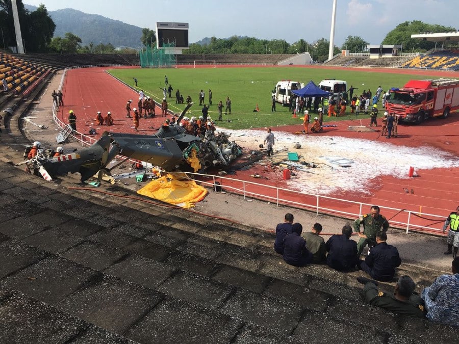 Firefighters are in the process of extracting the victims of a crash involving two military helicopters in Lumut today. Courtesy pic