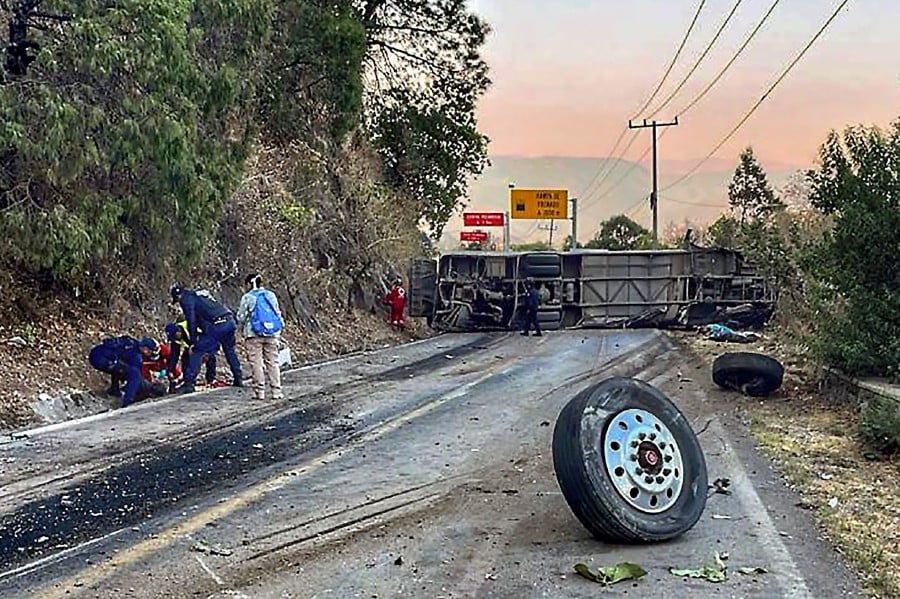 Rescuers working at the site of an accident after a bus overturned on the roadway on the outskirts of Mexico City, Mexico. - AFP PIC