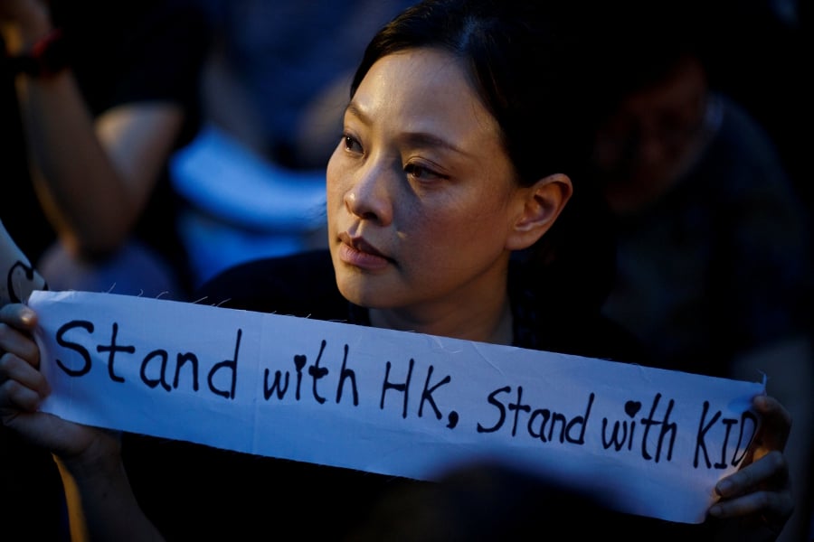 A woman holds a placard during a gathering of Hong Kong mothers to show their support for the city's young pro-democracy protesters.-Reuters