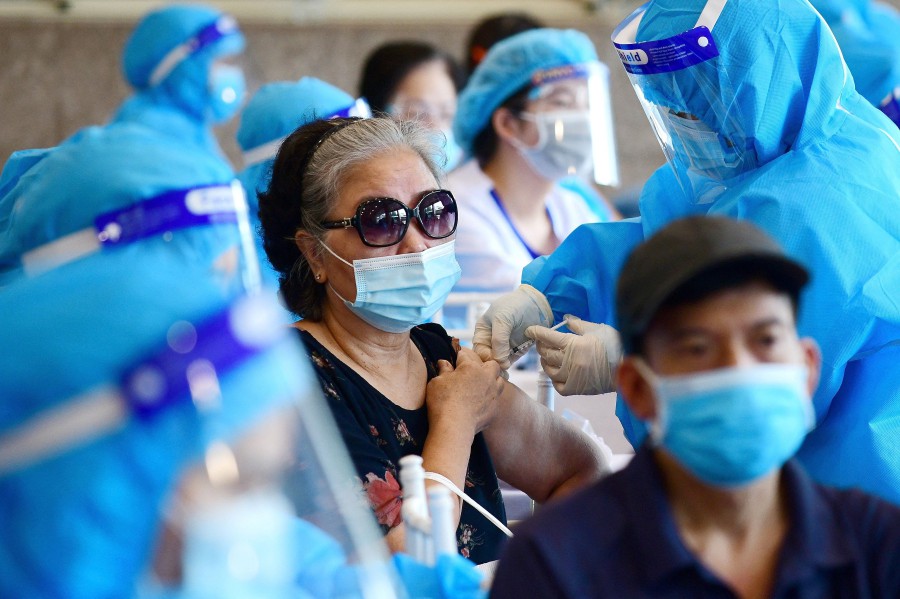 A woman (centre) receives the AstraZeneca Covid-19 coronavirus vaccine in Hanoi. (Photo by Nhac NGUYEN / AFP)