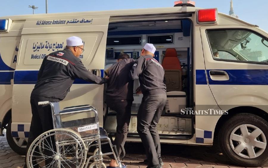 Tabung Haji (TH) personnel helping a pilgrim enter its ambulance for treatment. - NSTP/Husain Jahit
