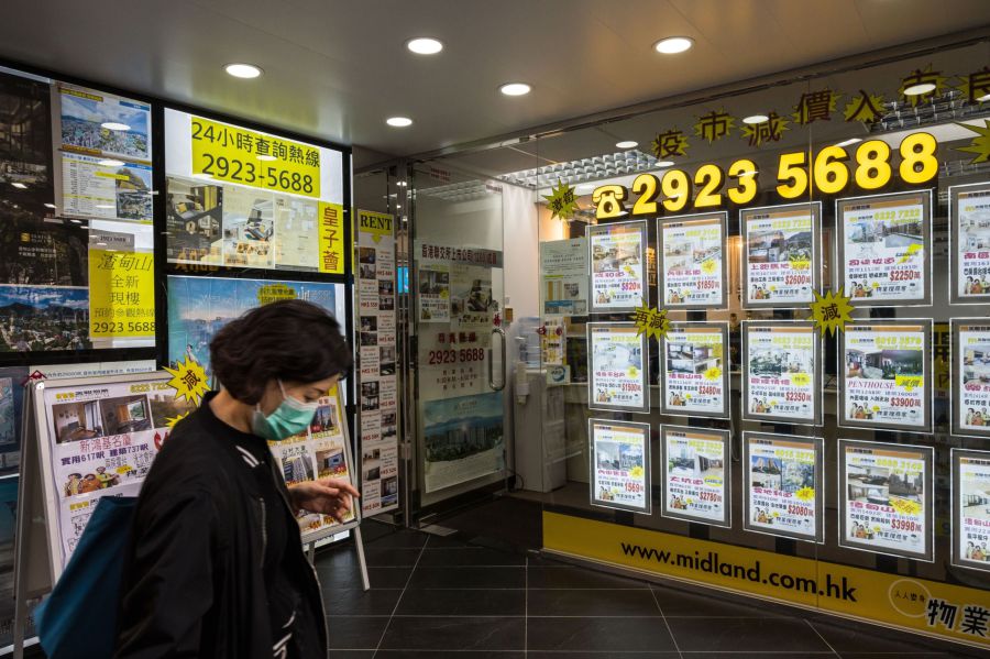 A pedestrians wearing protective mask walks past residential property advertisements displayed in the window of a Midland Realty store, operated by Midland Holdings Ltd., in Hong Kong, China, on Thursday, Feb. 20, 2020. Apartment rents in Hong Kong have dropped to the lowest in almost two years as people leave the city and home owners try to lease rather than sell.