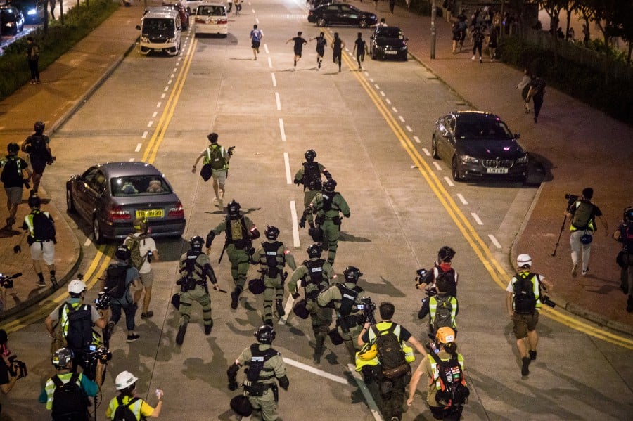  Riot police chase a group of protesters down a road on foot, following a rally at Chater Garden in the Central district in Hong Kong, China. - EPA