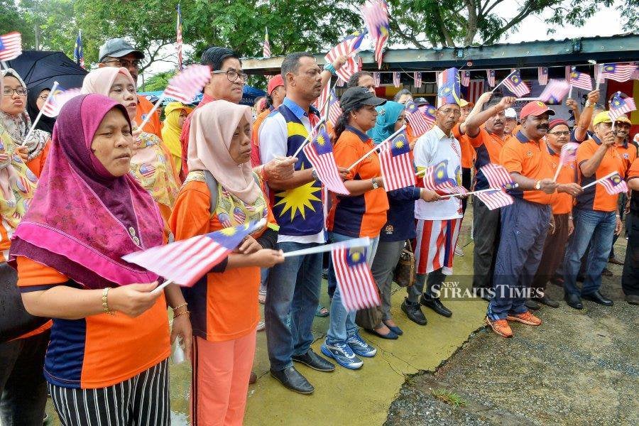 This file pic dated Sept 10, 2017, shows residents waving the Jalur Gemilang ahead of Klang District Unity programme convoy at Kawasan Rukun Tetangga (KRT) Taman Menara Maju, Klang. - NSTP file pic