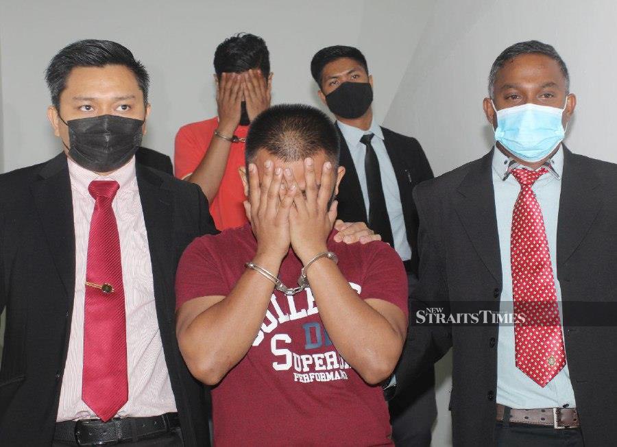  Immigration officers Mohamad Hariss Rosli (front) and Fasmawi Ab Wahab (back) cover their faces from being photographed as they are led to the Kota Baru Sessions’s Court. -NSTP/NIK ABDULLAH NIK OMAR