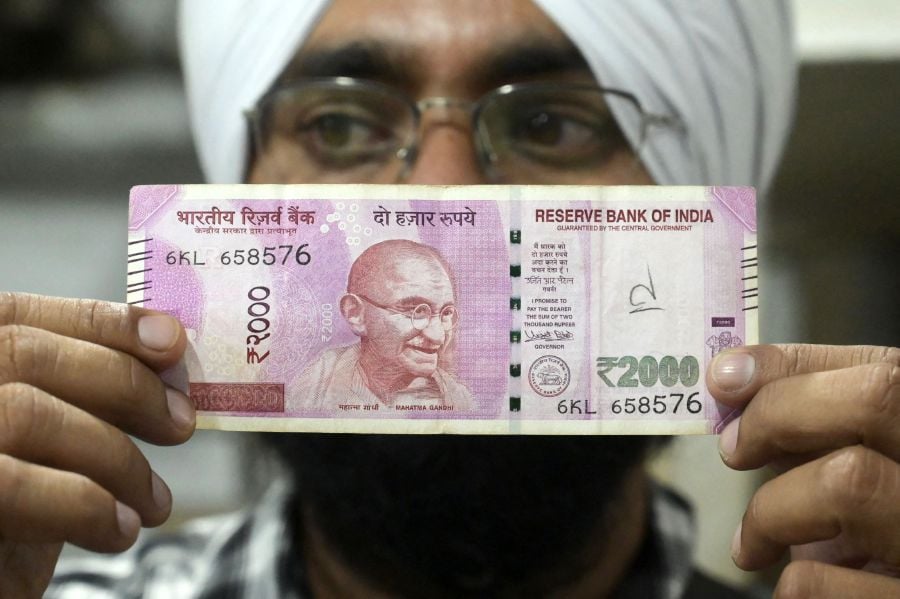 A Sikh man poses for a picture while holding a 2,000 INR (24.13 USD) banknote in Amritsar on May 19, 2023, after the Reserve Bank of India (RBI) announced the withdrawal of the 2,000 denomination banknotes from circulation. - AFP pic